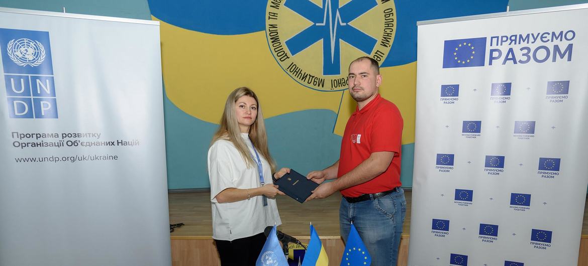 Специалист ПРООН вручает Евгению сертификат успешного прохождения курсов профессиональной подготовки. 