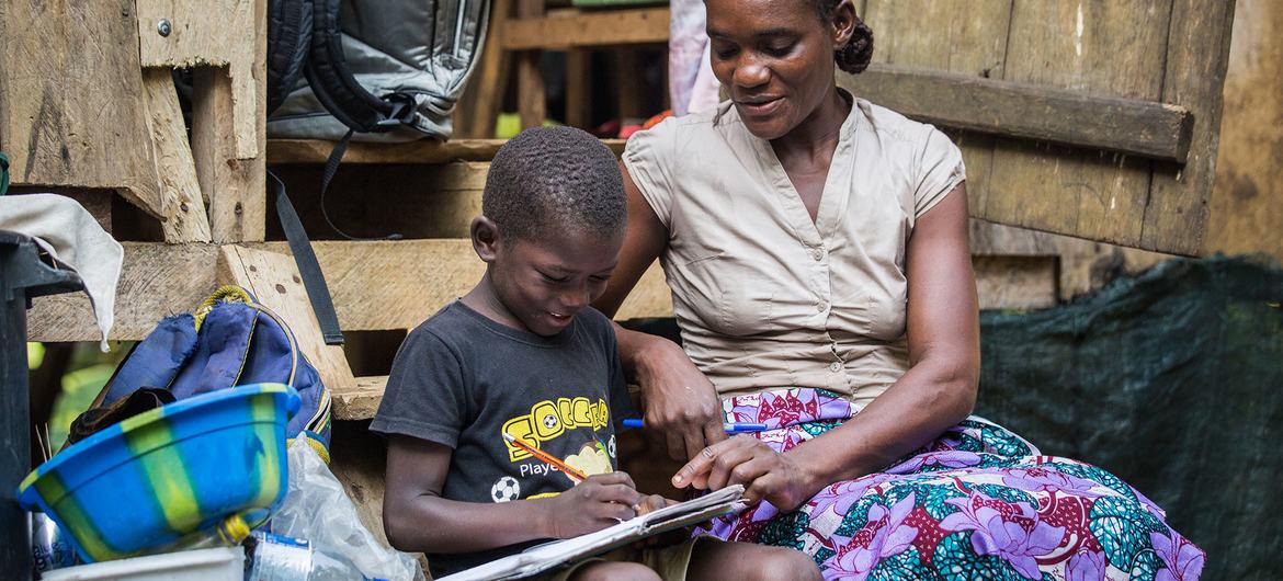 Uma mãe ajuda seu filho a fazer a lição de casa em São Tomé e Príncipe.