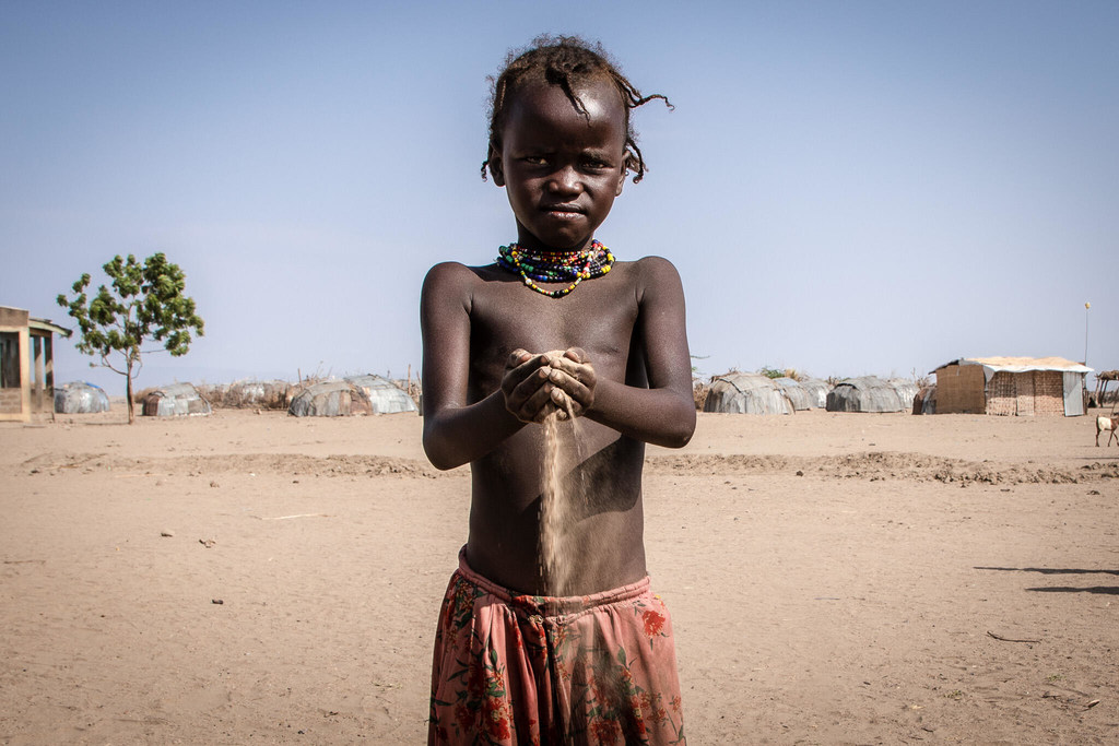 En Libemuket, Etiopía, un niño etíope sostiene arena entre sus manos mientras cae formando la figura de un reloj de arena, simbolizando el impacto del cambio climático y la sequía en la región.