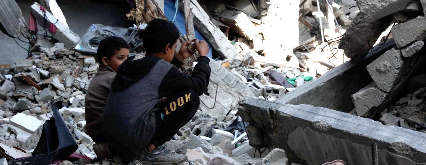 Deux jeunes garçons sont assis parmi les décombres d'un immeuble détruit à Gaza.
