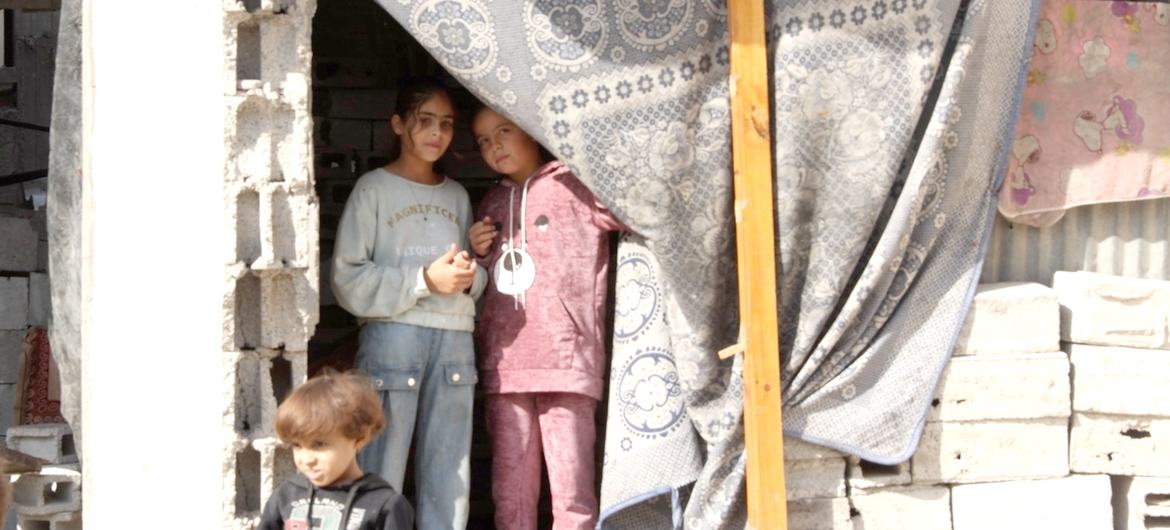 Selin Al-Dada y sus hermanos posan delante de lo que queda de su casa destruida.