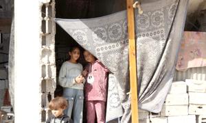 Selin Al-Dada y sus hermanos posan delante de lo que queda de su casa destruida.