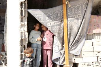 Selin Al-Dada y sus hermanos posan delante de lo que queda de su casa destruida.