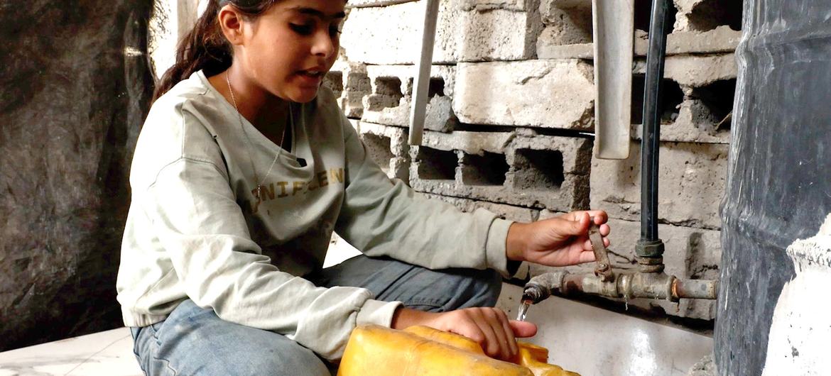 Selin Al-Dada, una niña de Gaza, llena un galón de plástico con agua potable.