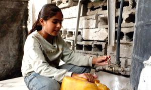 Selin Al-Dada, una niña de Gaza, llena un galón de plástico con agua potable.