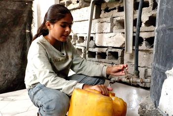 Selin Al-Dada, una niña de Gaza, llena un galón de plástico con agua potable.