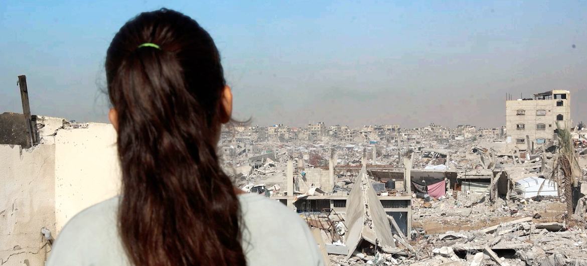 Девочка из Газы стоит на крыше своего поврежденного дома, глядя на разрушения по всему городу. Девочка из Газы стоит на крыше своего поврежденного дома, глядя на разрушения по всему городу.