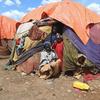 सोमालिया के बैदोआ में एक विस्थापित व्यक्ति शिविर में अपने अस्थायी आश्रय के बाहर एक माँ और उसके बच्चे.