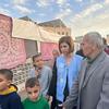 تقف جولييت توما، مديرة الاتصالات في وكالة الأونروا، في مخيم للنازحين في غزة إلى جانب رجل وعدة أطفال.