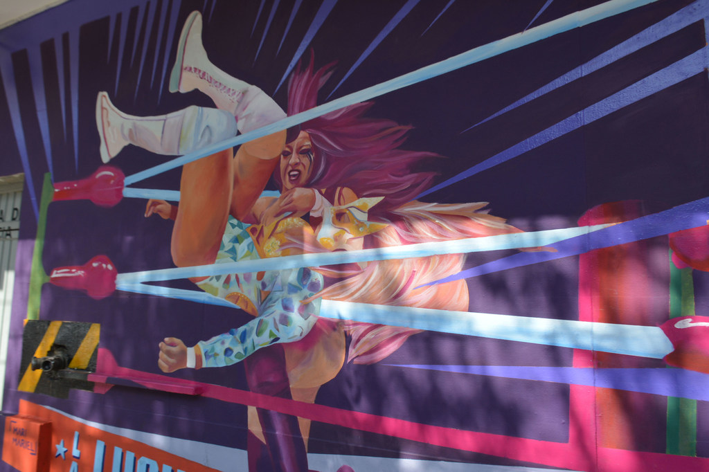 Mural de dos luchadoras en un combate de lucha libre en la fachada principal de la Arena México en la Ciudad de México.