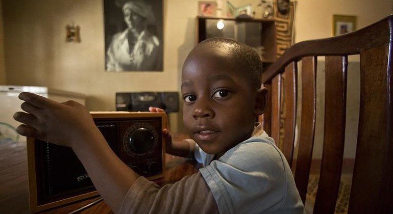刚果民主共和国的一名年轻男孩拿着古老的收音机,象征着COVID-19疫情期间的教育广播.