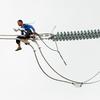 A worker in the Philippines installs a new electric cable atop a pylon. High-tension power lines made of copper are the backbone of electricity infrastructure worldwide.