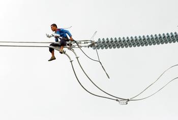 A worker in the Philippines installs a new electric cable atop a pylon. High-tension power lines made of copper are the backbone of electricity infrastructure worldwide.