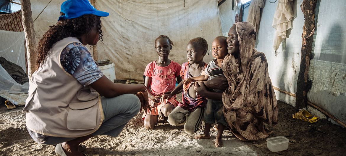 An IOM staff member talks to a family in South Sudan.
