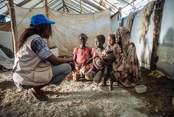An IOM staff member talks to a family in South Sudan.