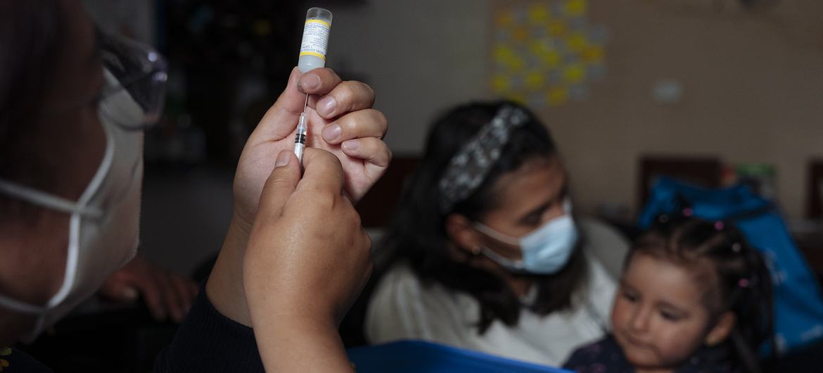 Una niña de dos años recibe una vacuna en su casa en Ecuador 