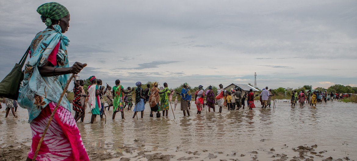 Communities make their way back to their temporary housing through flood water after distribution points run out of supplies, in Pibor, Jonglei, South Sudan, on 6 November 2019.