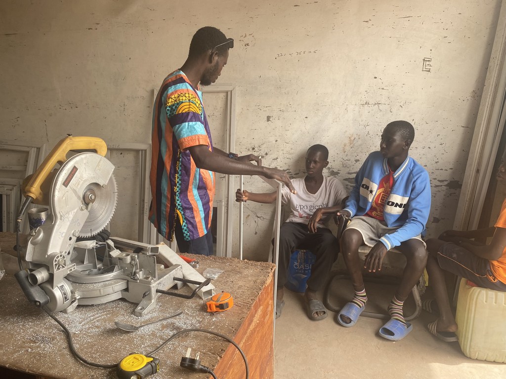 돌아온 이주민 Amadou Jobe가 감비아 Banjul의 작업장에서 견습생을 교육하고 있습니다.