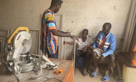 Mwanamume anawafundisha vijana wawili katika warsha huko Banjul, Gambia.