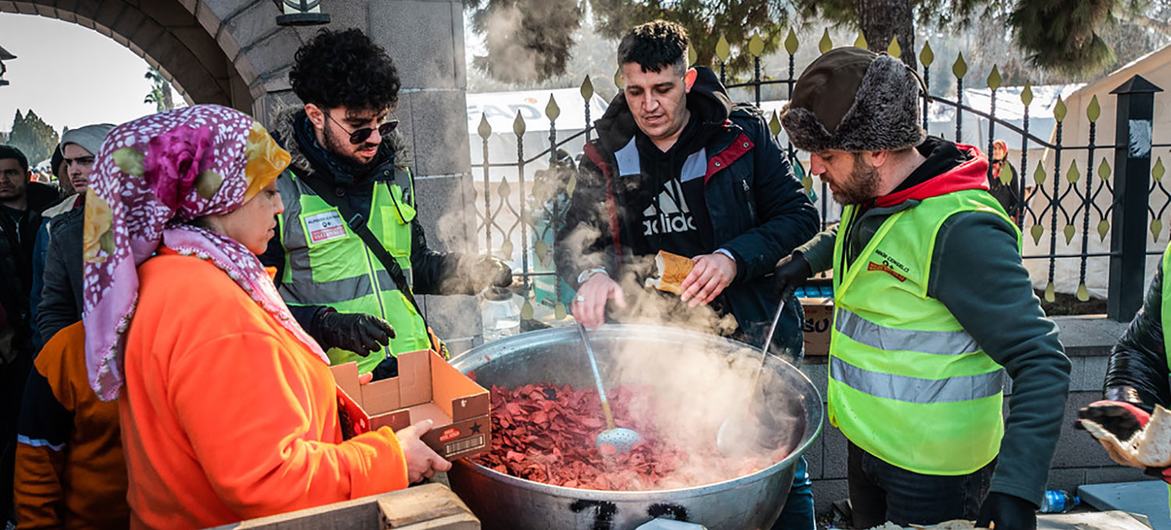 तुर्की में भूकम्प से विस्थापित लोगों को गर्म भोजन वितरित करते स्वयंसेवक.