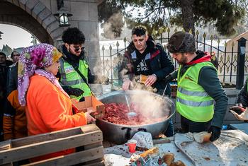 तुर्की में भूकम्प से विस्थापित लोगों को गर्म भोजन वितरित करते स्वयंसेवक.