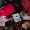 स्कूली पढ़ाई रुक जाने के बाद एक अफ़ग़ान लड़की अपने पिता की मदद से घर पर पढ़ाई करते हुए.