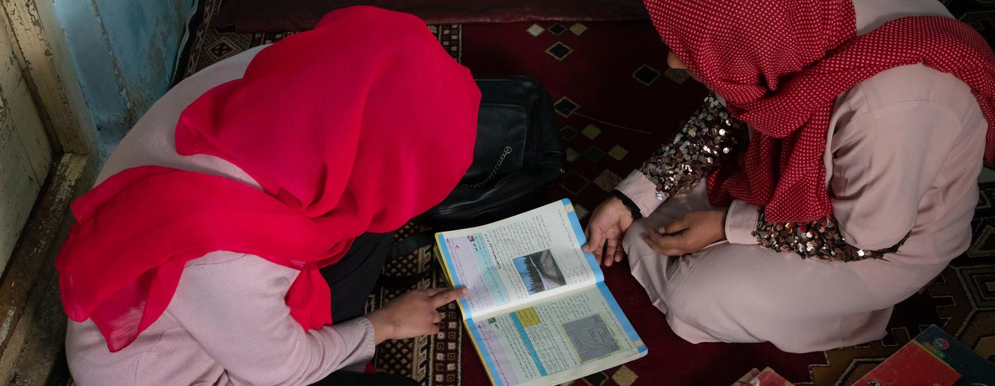 一名阿富汗女孩在被剥夺上学的权利后，在父亲的帮助下在家中继续学习。