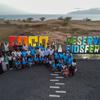 Um grupo de pessoas posando para uma foto em frente a uma grande placa com os dizeres 'Fogo Reserva da Biosfera', na Reserva da Biosfera do Fogo, em Cabo Verde.