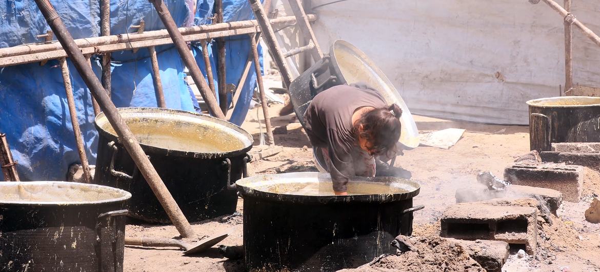 A young girl in Gaza trying to gather the remaining scraps of food from the cooking pot. A young girl in Gaza trying to gather the remaining scraps of food from the cooking pot.