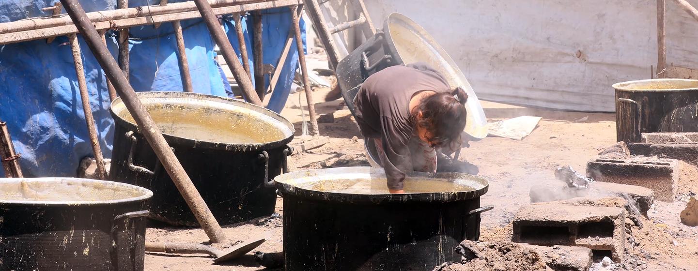 A young girl in Gaza trying to gather the remaining scraps of food from the cooking pot.