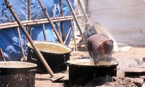 Una niña de Gaza intenta recoger los restos de comida que quedan en la olla.