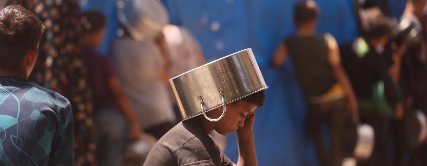 Un enfant se protège du soleil en attendant de recevoir de la nourriture à Gaza.