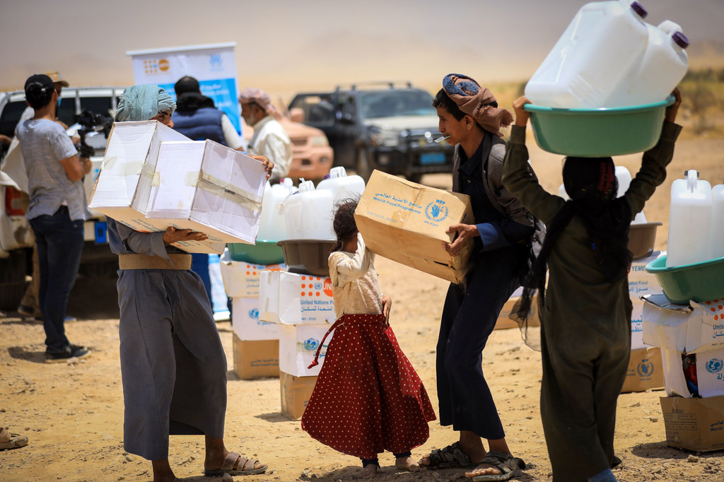 Des enfants transportent des rations alimentaires du PAM dans un camp de fortune pour personnes déplacées à Marib, au Yémen.
