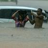 A man helps a woman after her car is stranded in waist-deep water. Globally rains are being more extreme due to impacts of climate change.