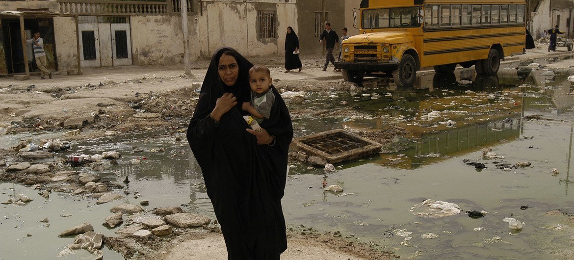 صورة من الأرشيف: أم تحمل طفلها الرضيع في طريقها إلى مركز للرعاية الصحية في مدينة البصرة العراقية.