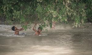 Children wade through a flooded canal in Pakistan, where this year's monsoon rains have left many families without homes, safe water or schooling. (file photo)