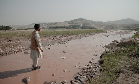 Hidayatullah Sapi do Unodc de pé no leito do “Rio Vermelho” e olhando para longe na região oriental do Afeganistão