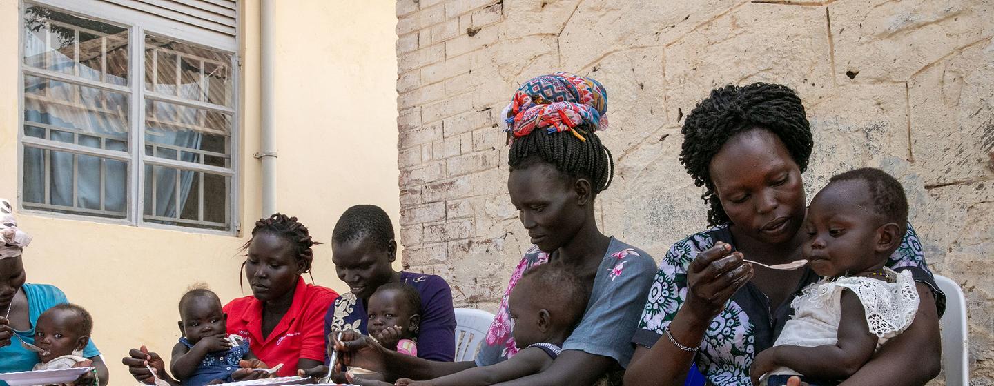 दक्षिण सूडान में महिलाएँ, एक पोषण केन्द्र पर अपने बच्चों को आहार दे रही हैं.