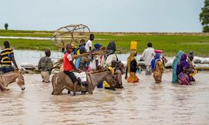 Residents of Rann, in north-east Nigeria, wade through the flooded main road, which is now inaccessible by vehicle.