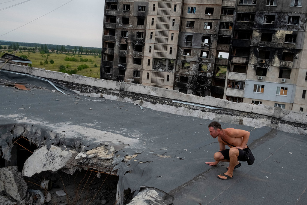 Dans la banlieue de Kharkiv, en Ukraine, un homme inspecte les dégâts causés par des tirs d'artillerie et des bombardements.