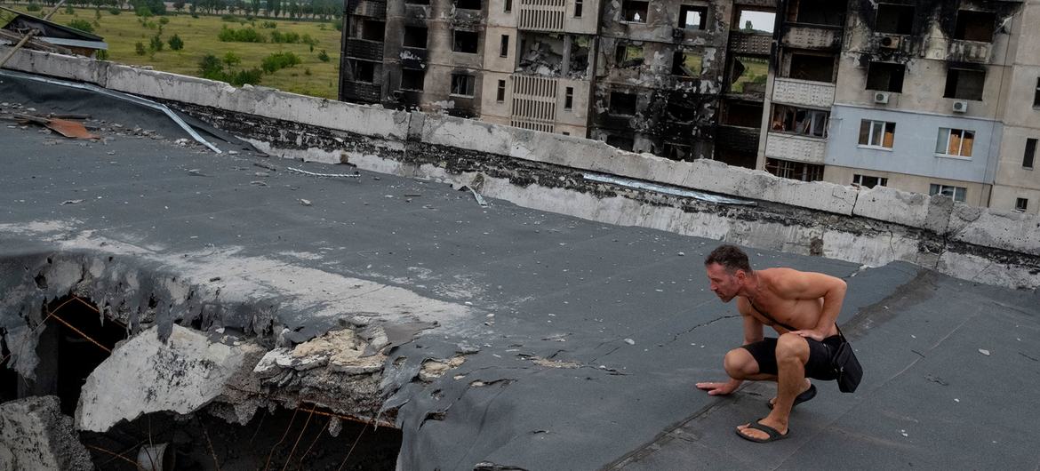 A man inspects damage on the roof of an apartment complex destroyed by artillery and air strikes in a Kharkiv suburb..