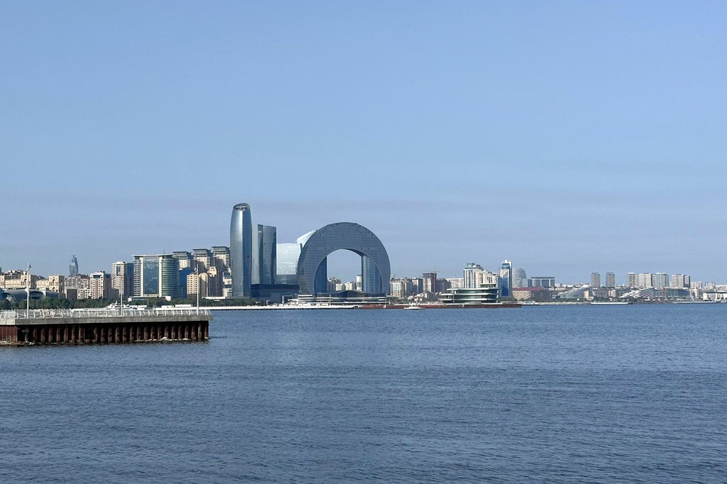 Uma vista do horizonte da cidade de Baku a partir do Mar Cáspio, com as Torres da Chama e o Centro Internacional de Convenções.