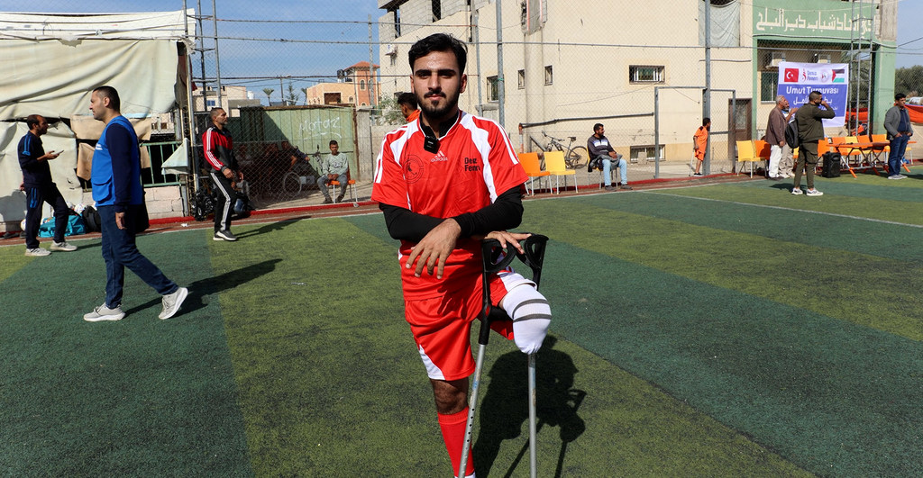 يقف عبد الله أبو مخيمر، عضو المنتخب الوطني الفلسطيني لكرة القدم لذوي الإعاقة، على ملعب كرة قدم في غزة.
