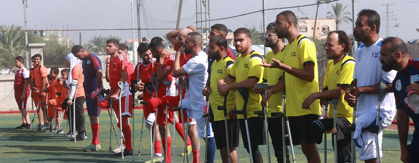 Jugadores de fútbol amputados se alinean en un campo deportivo en Gaza.
