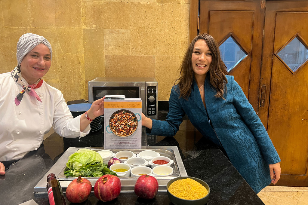 La embajadora de buena voluntad del Programa Mundial de Alimentos, la chef Manal Al Alem, y la fundadora de la ONG Kitchen Connection, Earlene Cruz, sostienen el libro de cocina en apoyo de las Naciones Unidas.