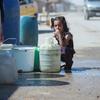 在叙利亚东北部哈塞克市，一名女童蹲在运水站旁边。 