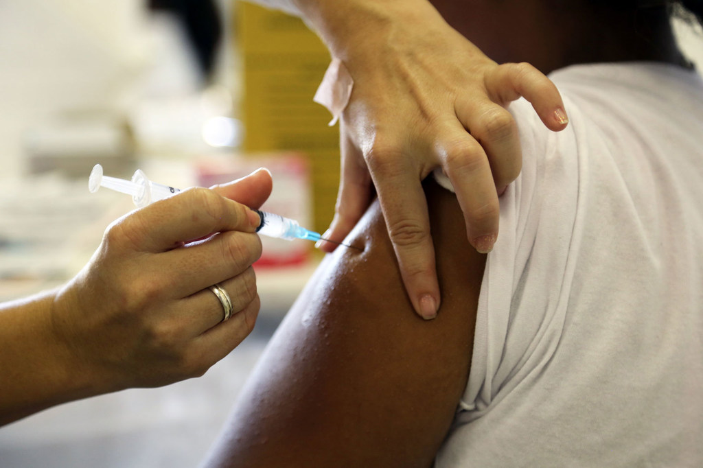 Una trabajadora sanitaria administra una inyección de la vacuna contra el VPH en la parte superior del brazo de una niña en una clínica de São Paulo, Brasil.
