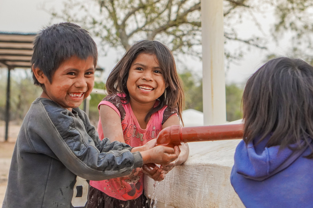 Niños indígenas beben agua de una cisterna en Las Palmitas, Argentina.