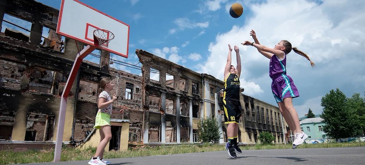 Des enfants jouent au basket dans une école de Kharkiv détruite au début de la guerre. L'école n'a pas encore été réparée, mais les enfants peuvent au moins retrouver un certain sens de la normalité en jouant dehors ensemble.
