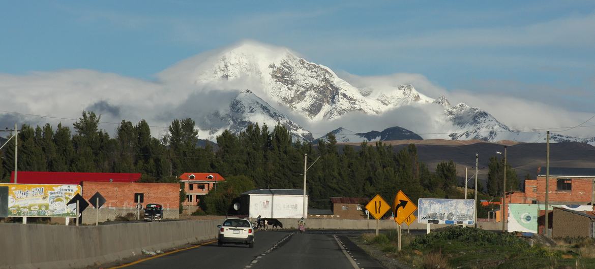 Vista de una carretera en El Alto, Bolivia, con la cordillera de los Andes cubierta de nieve al fondo.